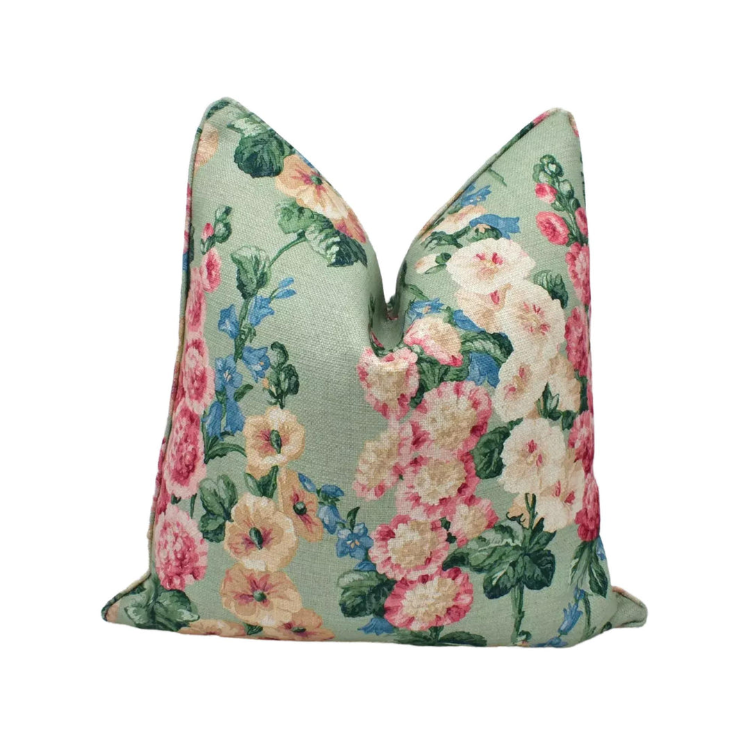 A green and pink floral print pillow with a repeating pattern of flowers and leaves.