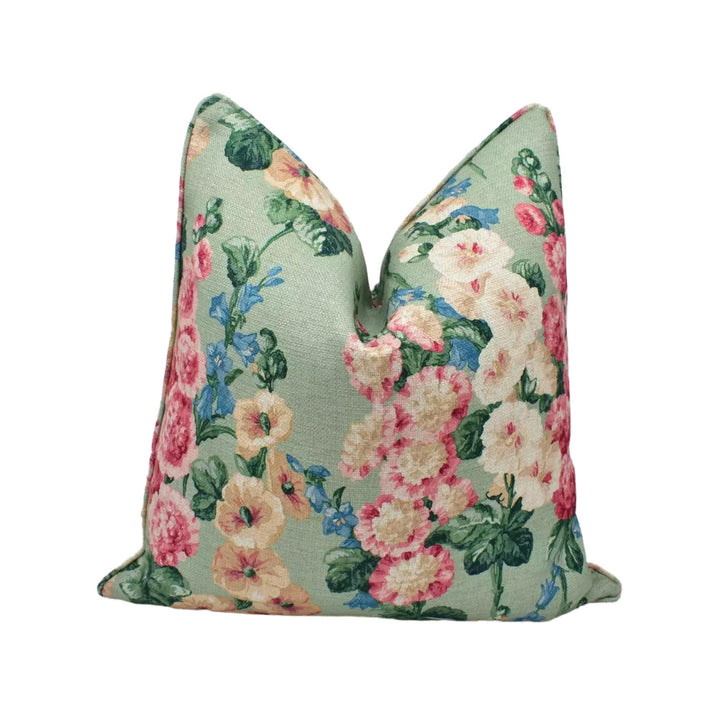 A green and pink floral print pillow with a repeating pattern of flowers and leaves.