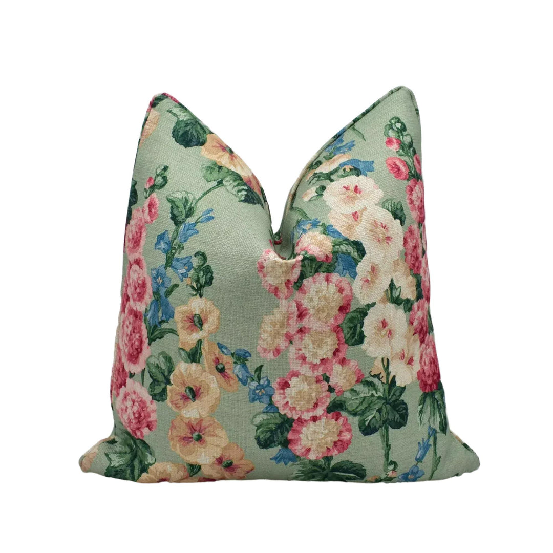 A decorative pillow with a floral print in shades of green, pink, and white.