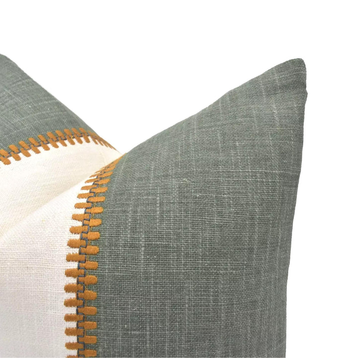 A close-up view of a green and white pillow with a textured fabric and a decorative border.
