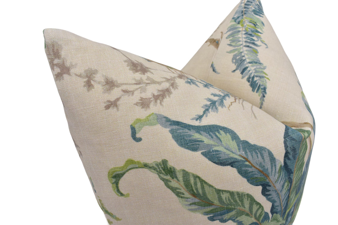a close-up view of a beige fabric with a pattern of green and blue leaves, resembling a tropical plant or palm tree.