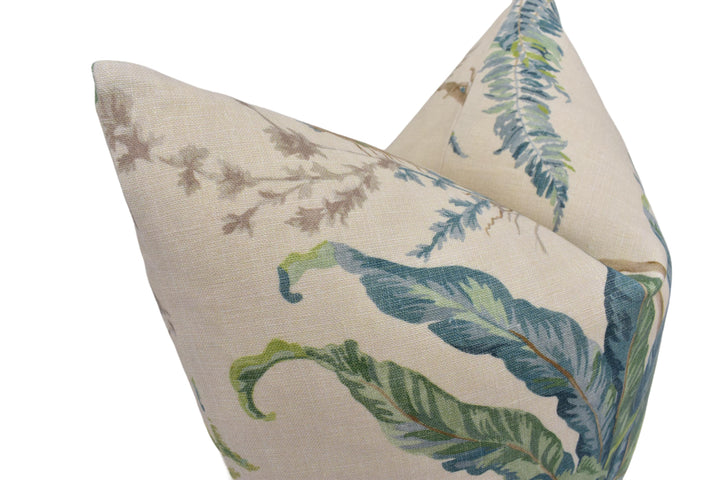 a close-up view of a beige fabric with a pattern of green and blue leaves, resembling a tropical plant or palm tree.
