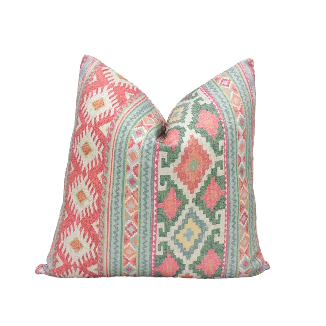 A decorative pillow with a vibrant, colorful pattern of geometric shapes and designs in shades of red, green, and yellow.