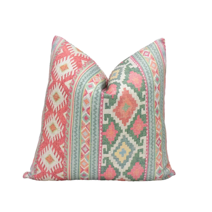 A decorative pillow with a vibrant, colorful pattern of geometric shapes and designs in shades of red, green, and yellow.