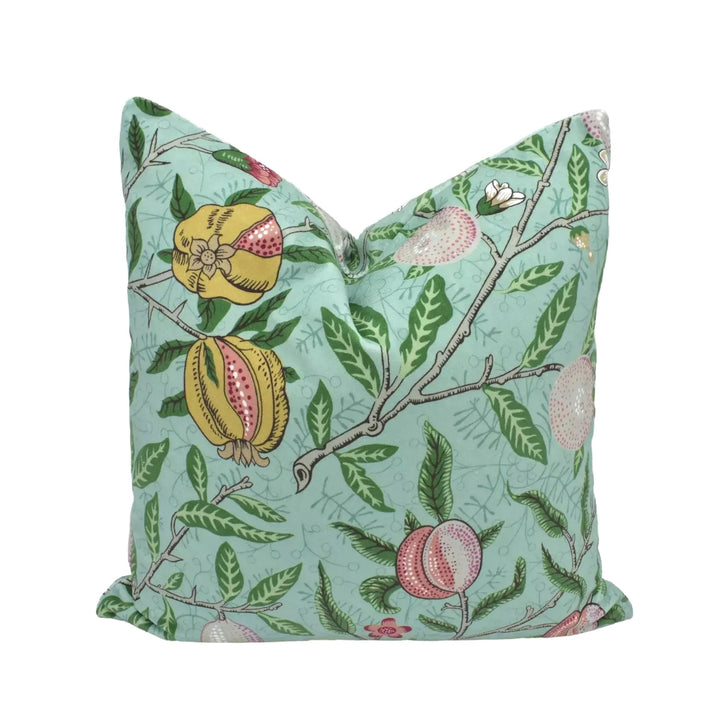 A decorative pillow with a vibrant floral pattern of pomegranate leaves and flowers in shades of green and pink.