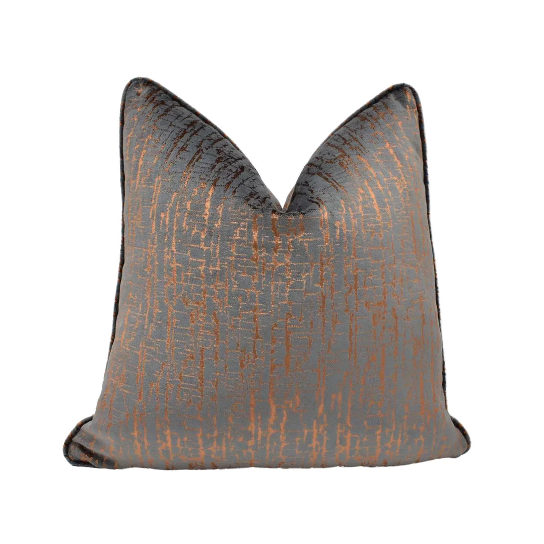 a gray and orange textured pillow with a metallic sheen, placed against a white background.