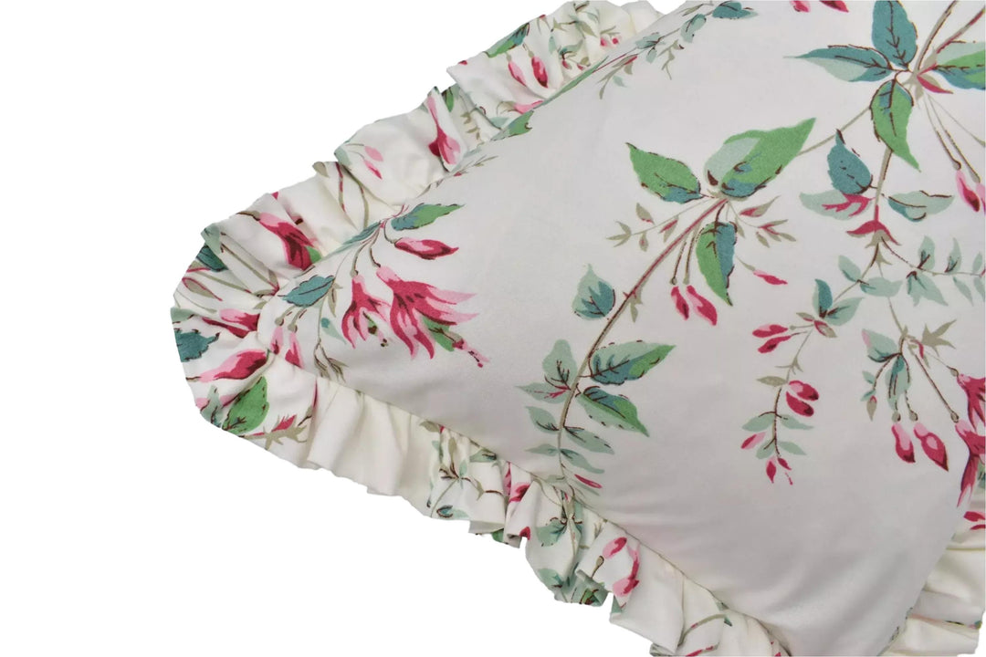 A close-up view of a white pillow with a floral print design, featuring green leaves and pink flowers.