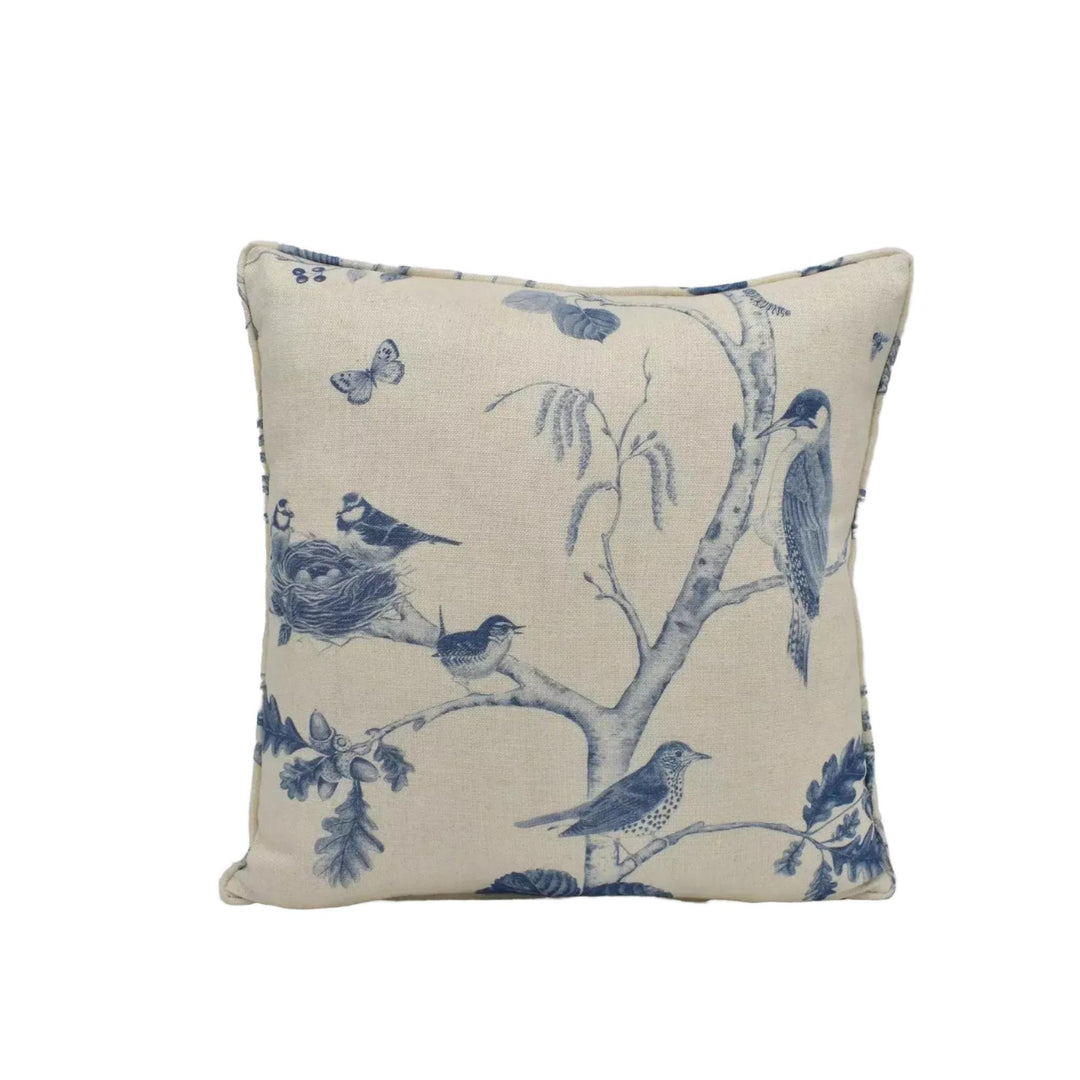 A square throw pillow with a blue and white floral pattern depicting birds perched on branches.
