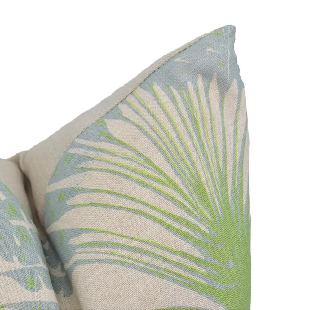 a close-up view of a decorative pillow with a palm tree pattern in shades of green and blue.