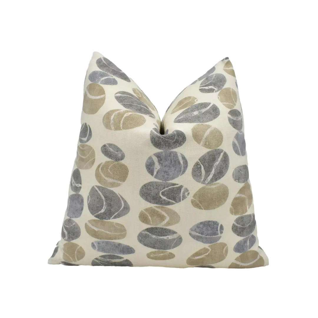 a pillow with a repeating pattern of gray and brown circles on a cream-colored background.