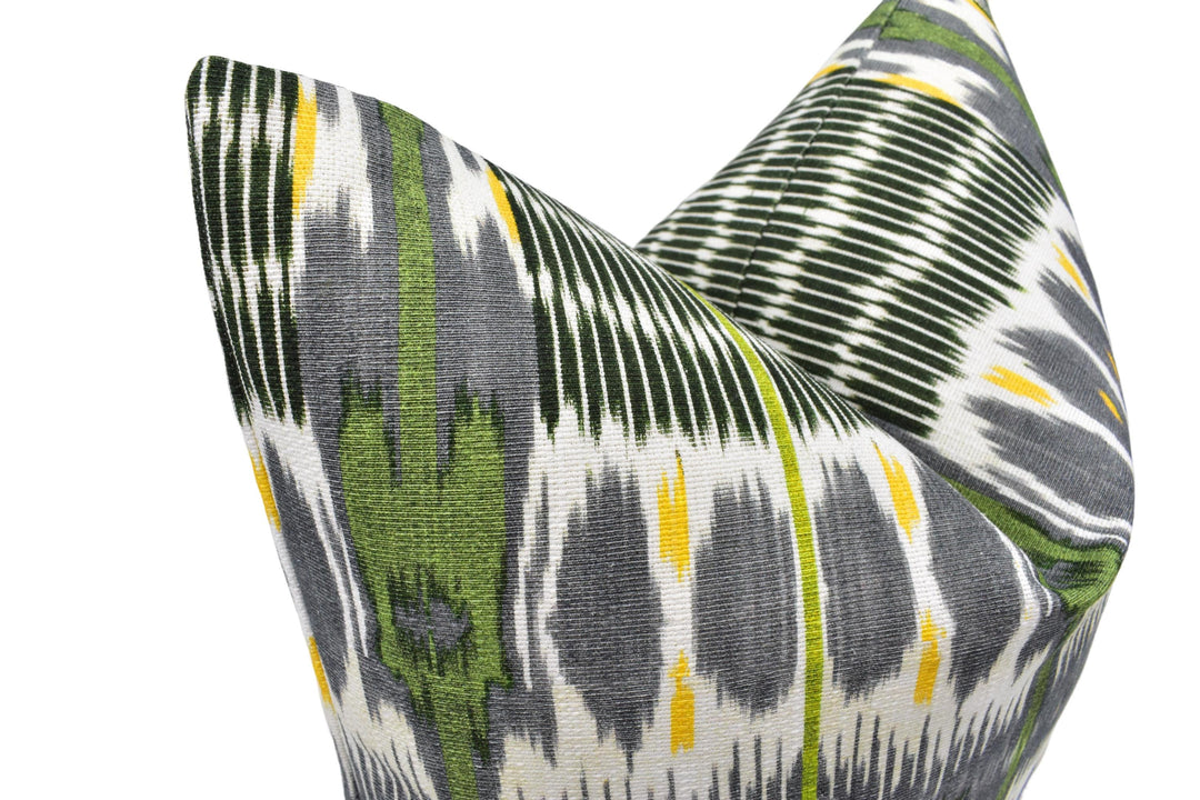 a close-up view of a decorative pillow with a vibrant, colorful pattern featuring green, gray, and yellow stripes and shapes.