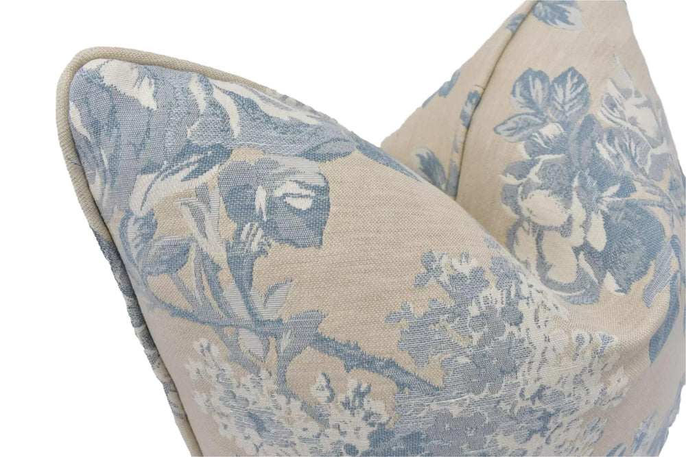 a close-up view of a decorative pillow with a floral pattern in shades of blue and beige.