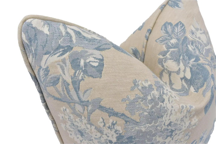 a close-up view of a decorative pillow with a floral pattern in shades of blue and beige.