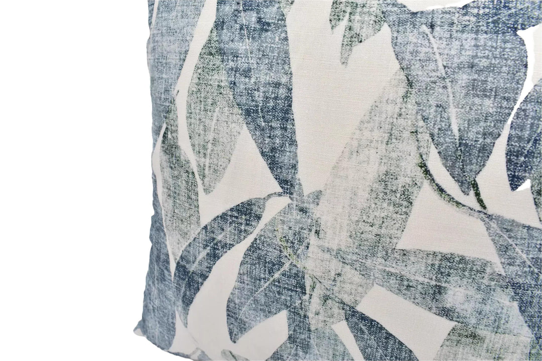 a close-up view of a decorative pillow with a leafy pattern in shades of blue and white.