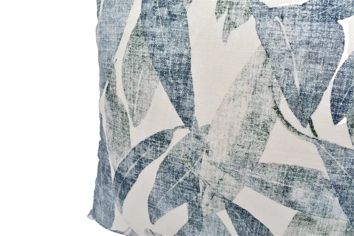 a close-up view of a decorative pillow with a leafy pattern in shades of blue and white.