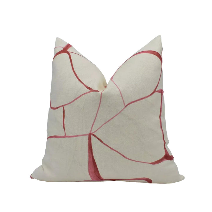 A white pillow with a red abstract pattern on it.