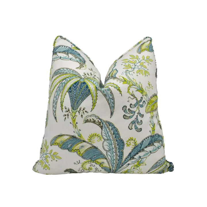 a decorative pillow with a tropical leaf pattern in shades of green and blue.