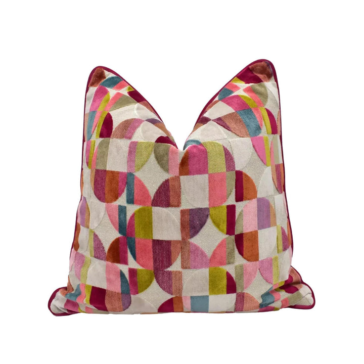 A colorful, geometric patterned pillow with a mix of pink, green, yellow, and orange colors.