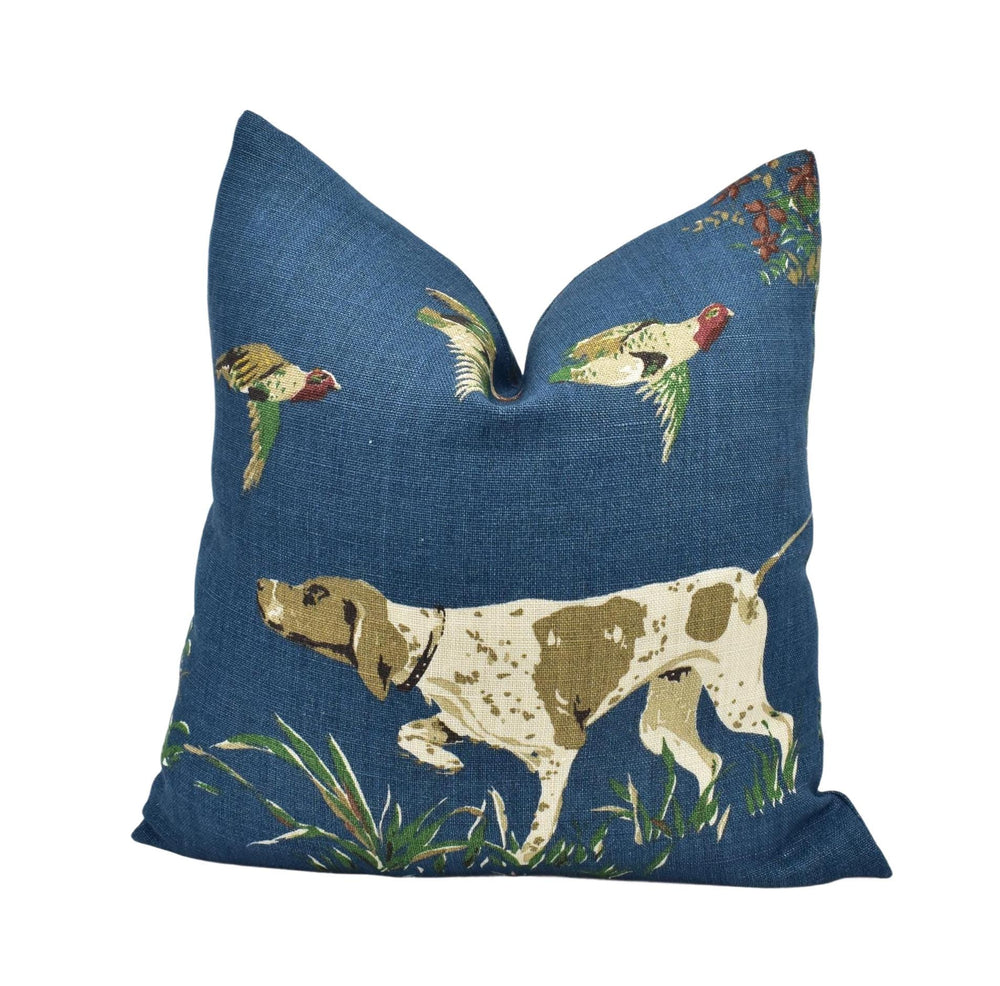 A blue throw pillow with a design depicting a dog and birds in flight.