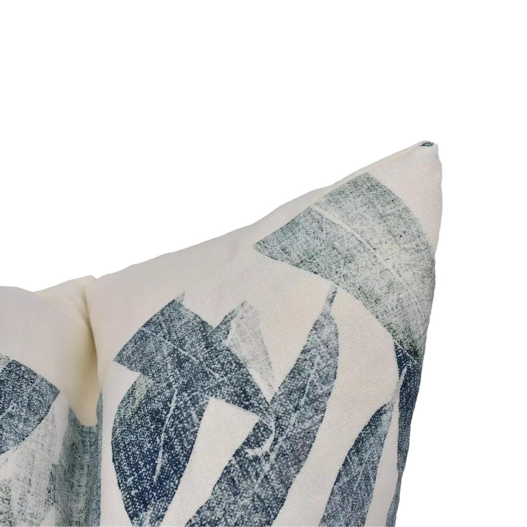 a close-up view of a white pillow with a blue leaf pattern, resting on a white surface.