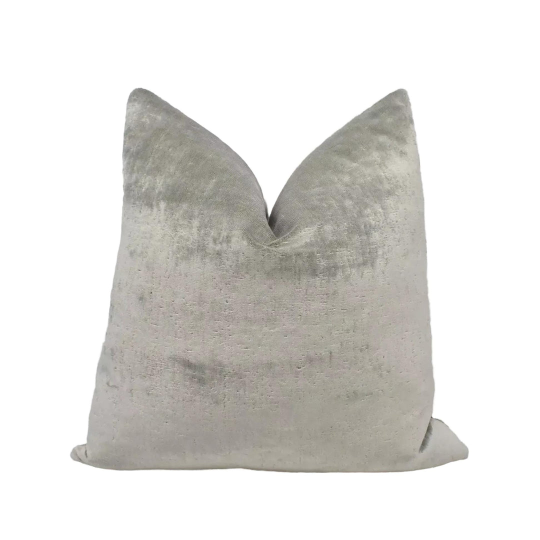 A gray velvet pillow with a textured surface.