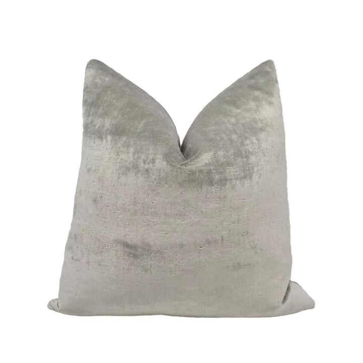 A gray velvet pillow with a textured surface.