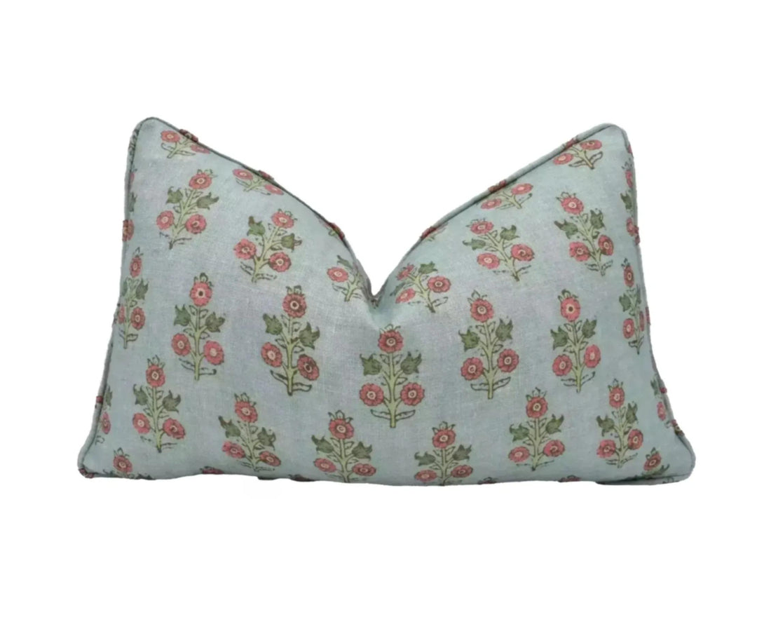 A light blue pillow with a repeating floral pattern in shades of green and red.