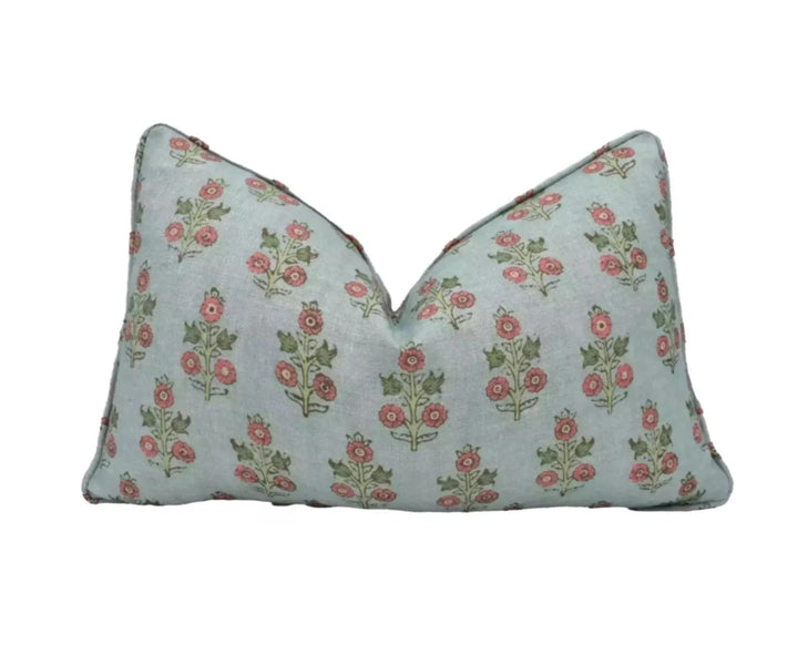 A light blue pillow with a repeating floral pattern in shades of green and red.