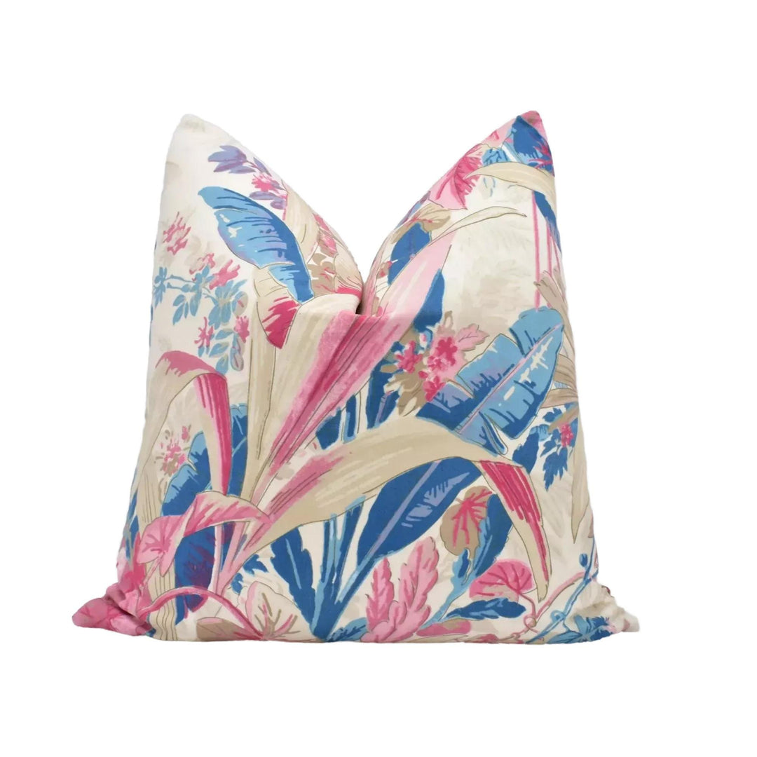 A decorative throw pillow with a tropical leaf pattern in shades of pink, blue, and green.