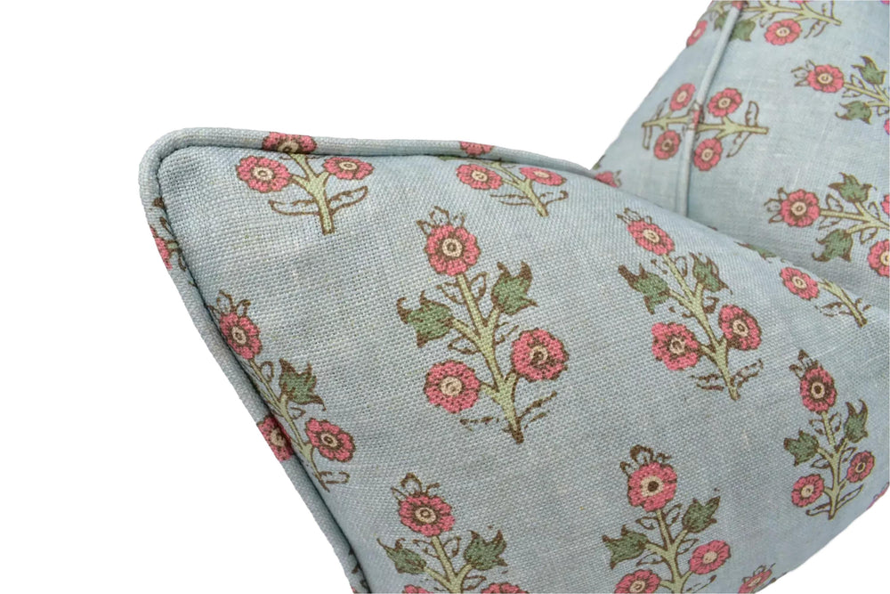 a close-up view of a light blue fabric with a floral pattern of pink flowers and green leaves.