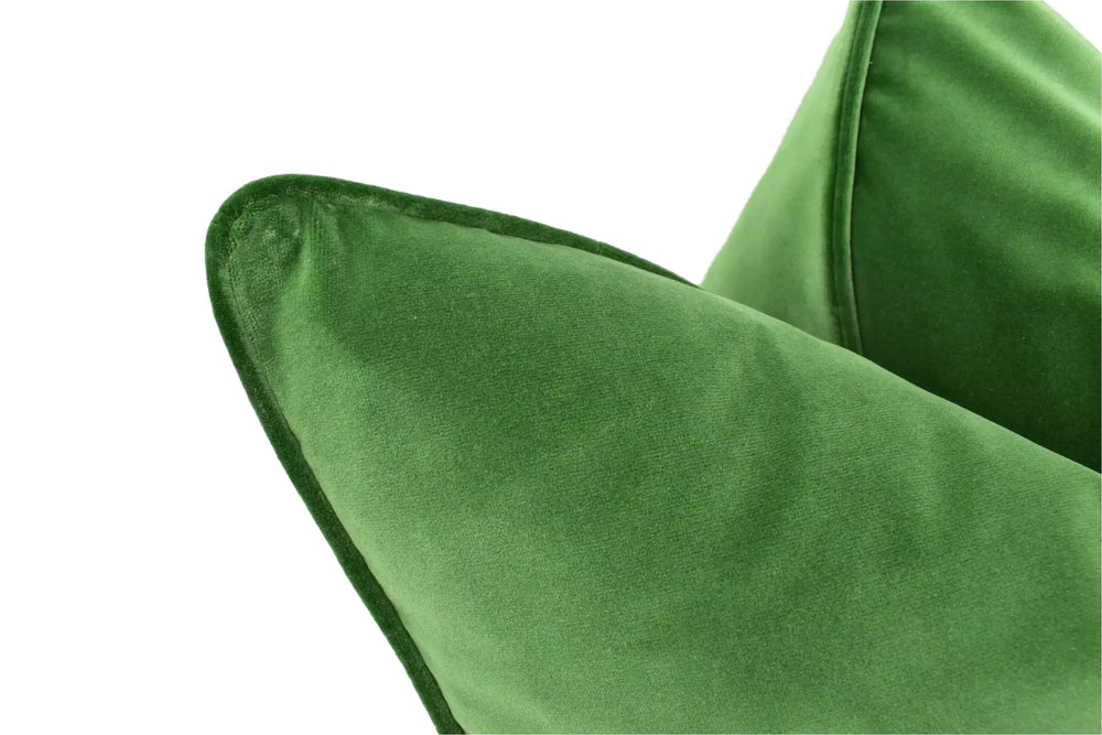 A close-up view of a green velvet pillow, with a smooth and shiny texture.