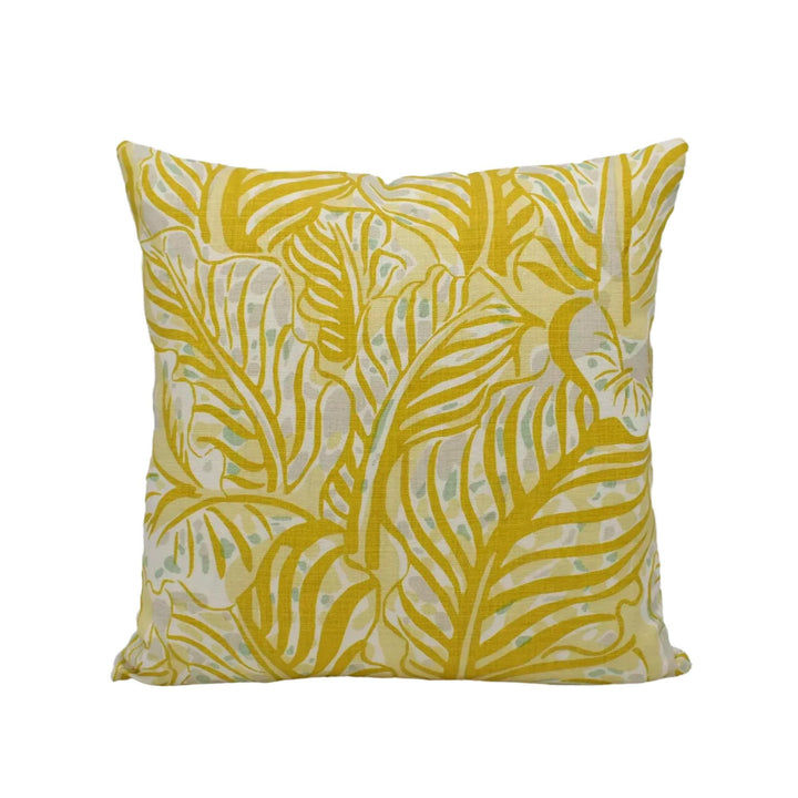 A square throw pillow with a yellow and green leaf pattern.