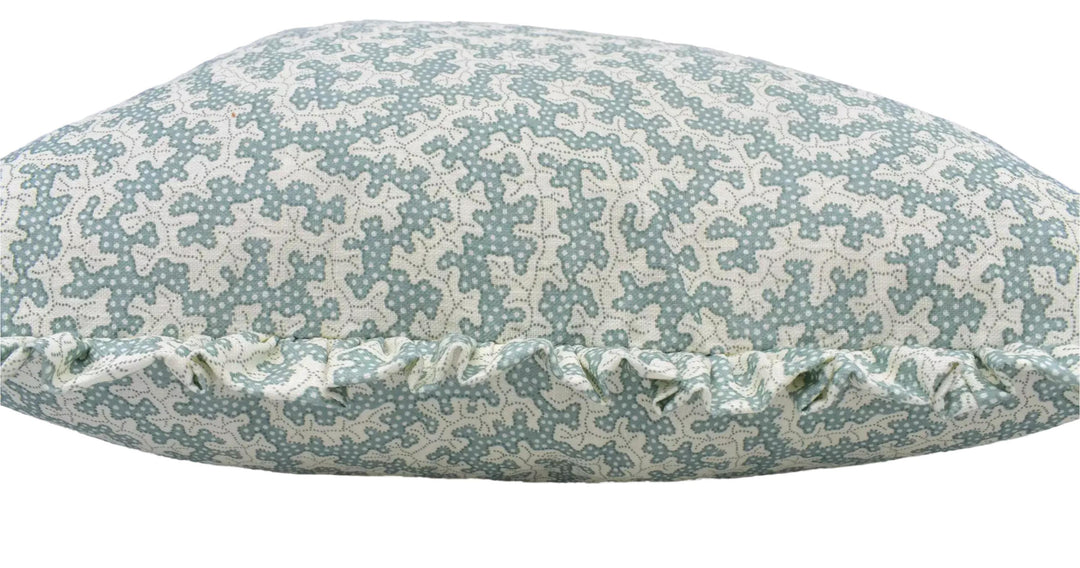 A close-up image of a decorative pillow with a pattern of small white flowers or dots on a light blue background.