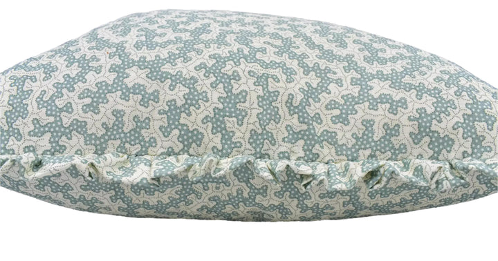 A close-up image of a decorative pillow with a pattern of small white flowers or dots on a light blue background.