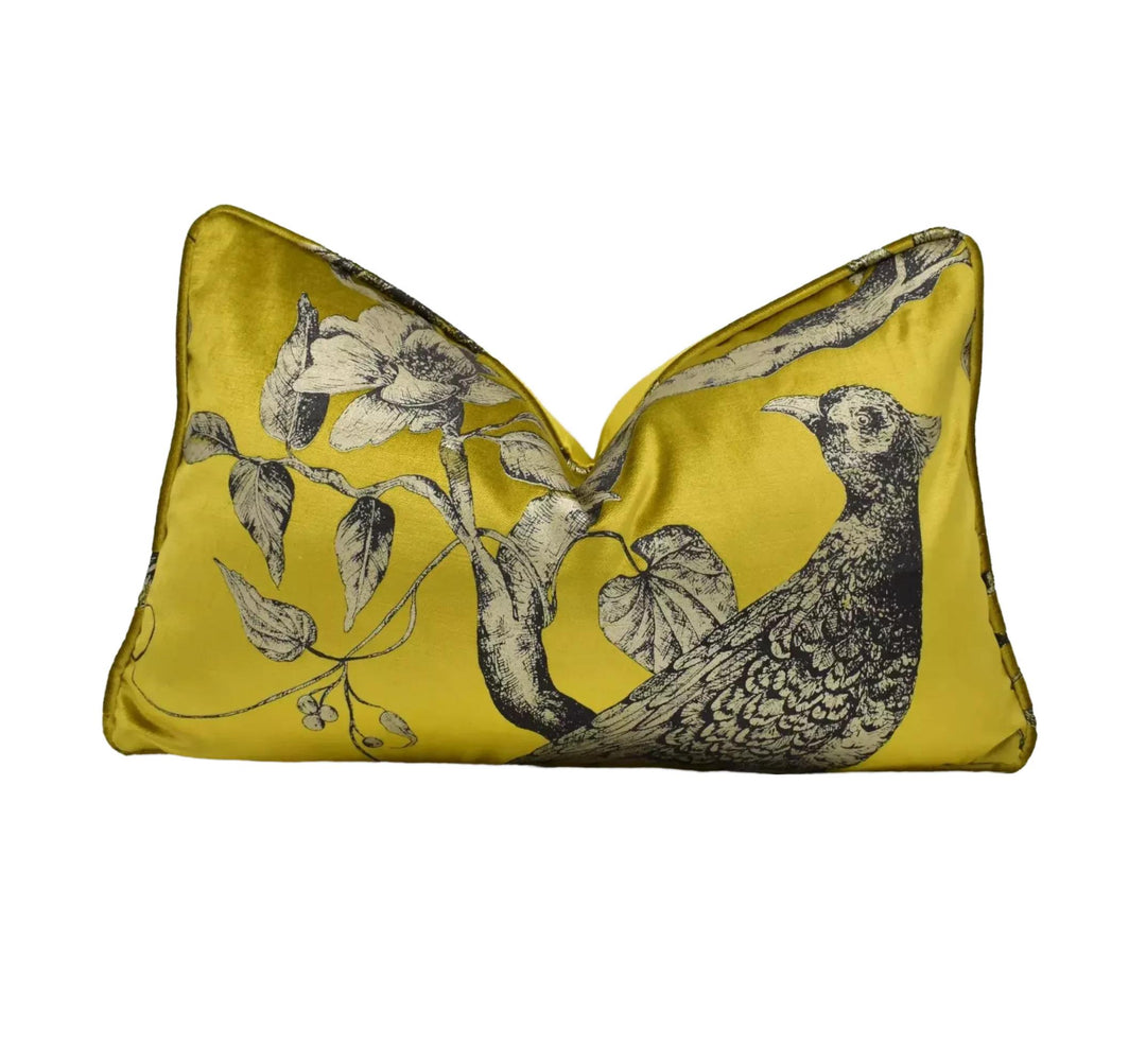 A yellow pillow with a black and white illustration of a bird perched on a branch.