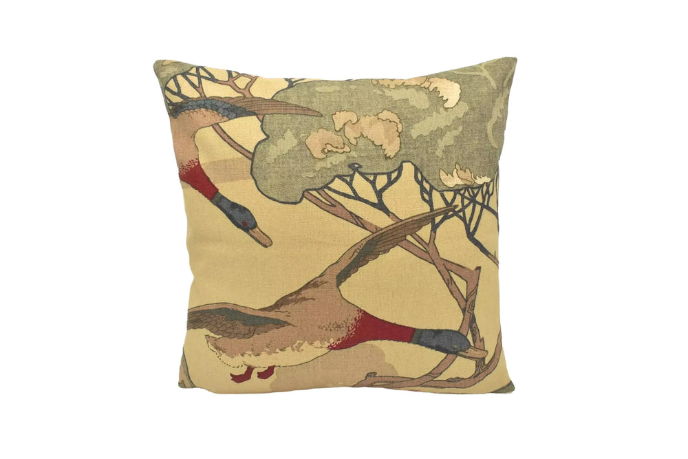 A decorative throw pillow with a nature-inspired design featuring two ducks in flight against a tree background.