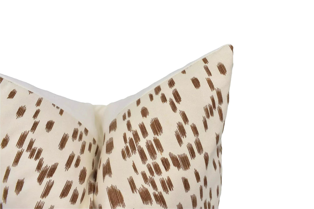 a close-up view of a beige pillow with a brown pattern, placed against a white background.