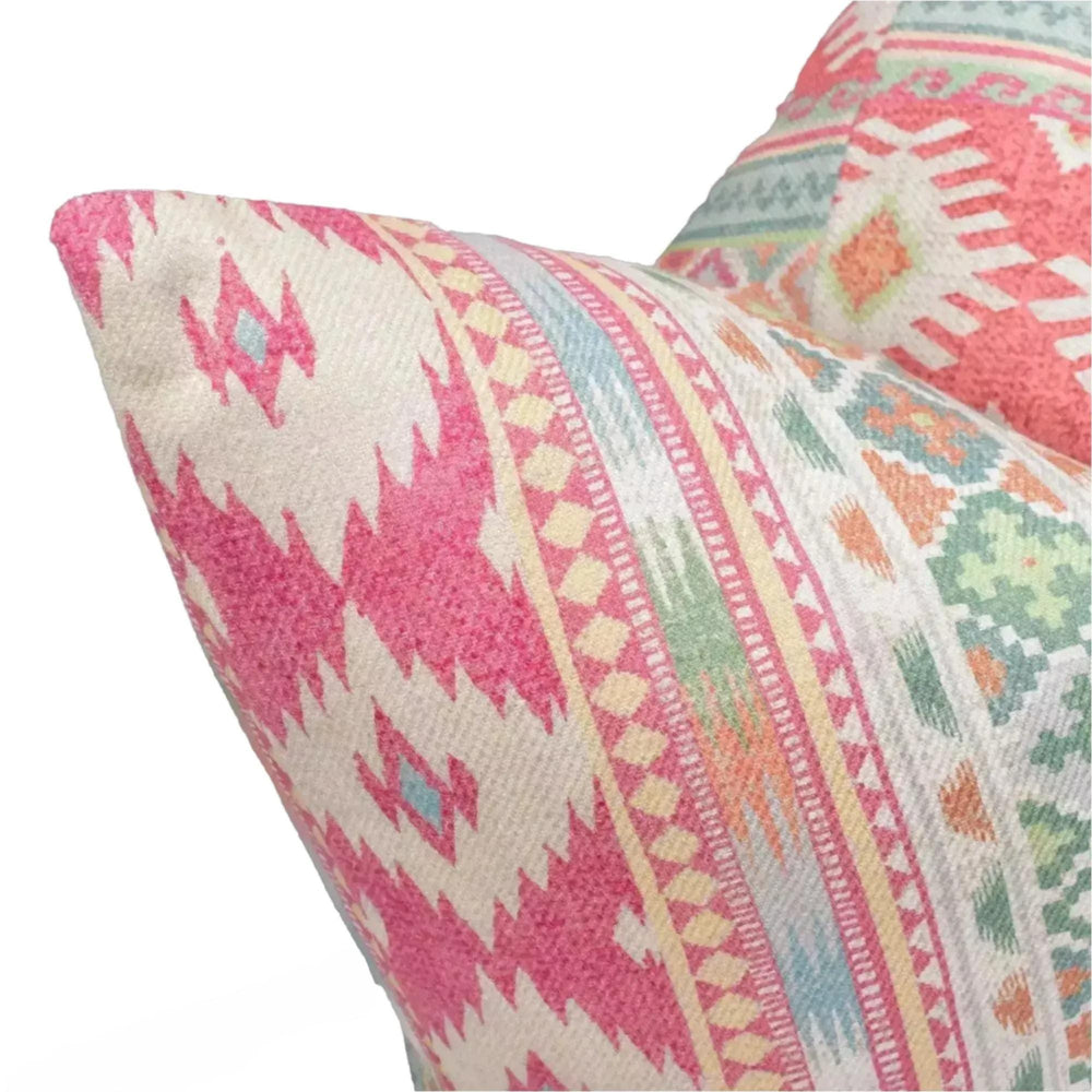 A close-up view of a vibrant, patterned pillow with a mix of pink, white, and green colors.