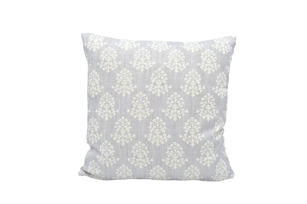 A gray and white patterned throw pillow is placed against a white wall.