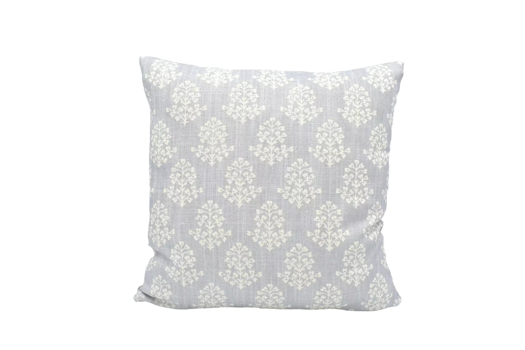 A gray and white patterned throw pillow is placed against a white wall.