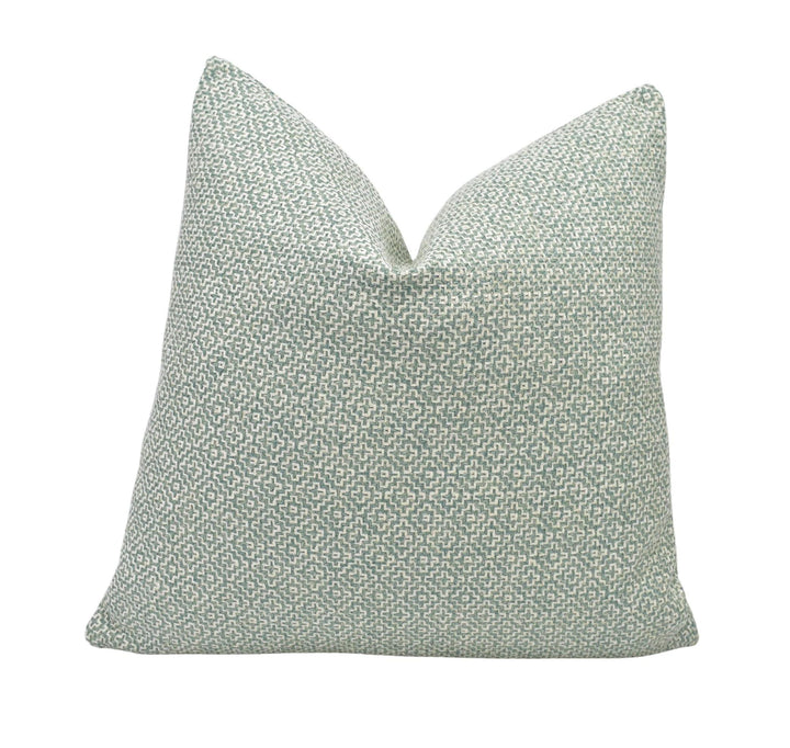 a green and white pillow on a white background