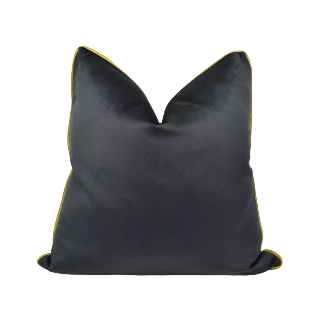A black velvet throw pillow with a gold trim.