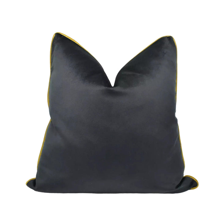 A black velvet throw pillow with a gold trim.