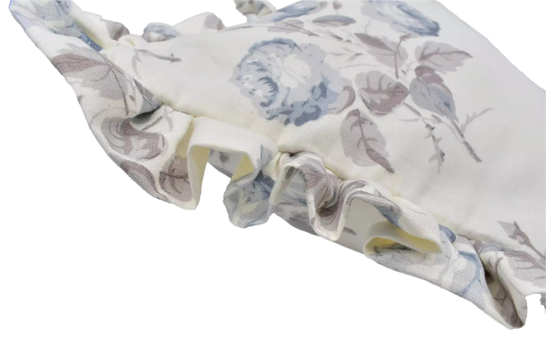 A close-up view of a white fabric with a floral pattern, featuring ruffled edges and a delicate, textured appearance.