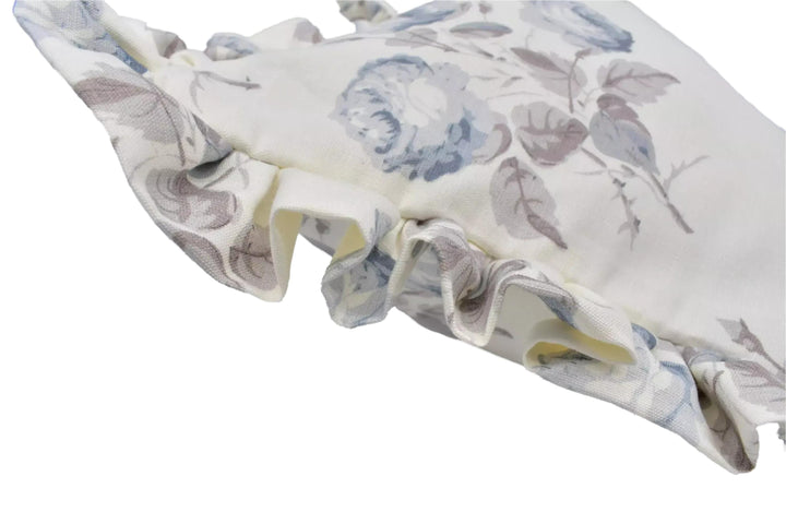 A close-up view of a white fabric with a floral pattern, featuring ruffled edges and a delicate, textured appearance.