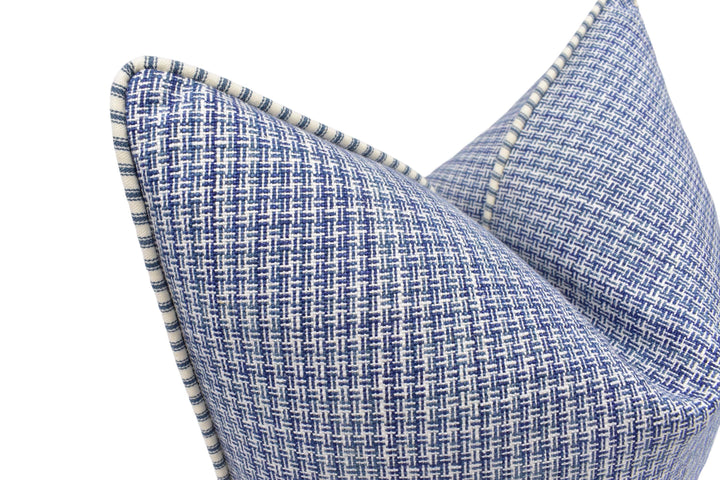 A close-up view of a blue and white woven pillow with a textured pattern.