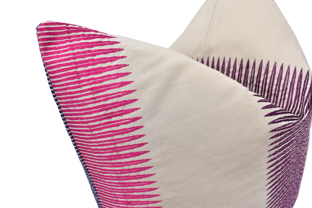 A close-up image of a decorative pillow with a striped pattern in shades of pink and white.