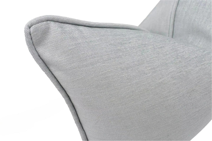 A close-up view of a gray fabric pillow, with a textured surface and a slight curve at the top.