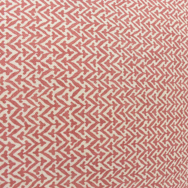 a close-up view of a fabric with a repeating pattern of red and white triangles. The pattern is arranged in a diagonal direction, creating a zigzag effect across the fabric. The fabric appears to be made of a soft, textured material, possibly cotton or linen.
