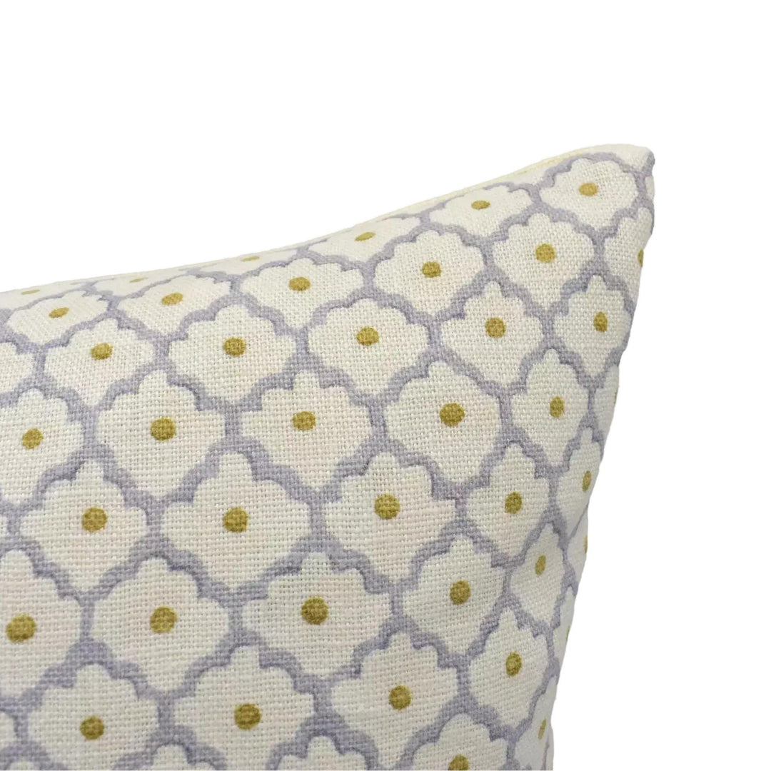 A close-up view of a decorative pillow with a repeating pattern of white and gold floral designs.
